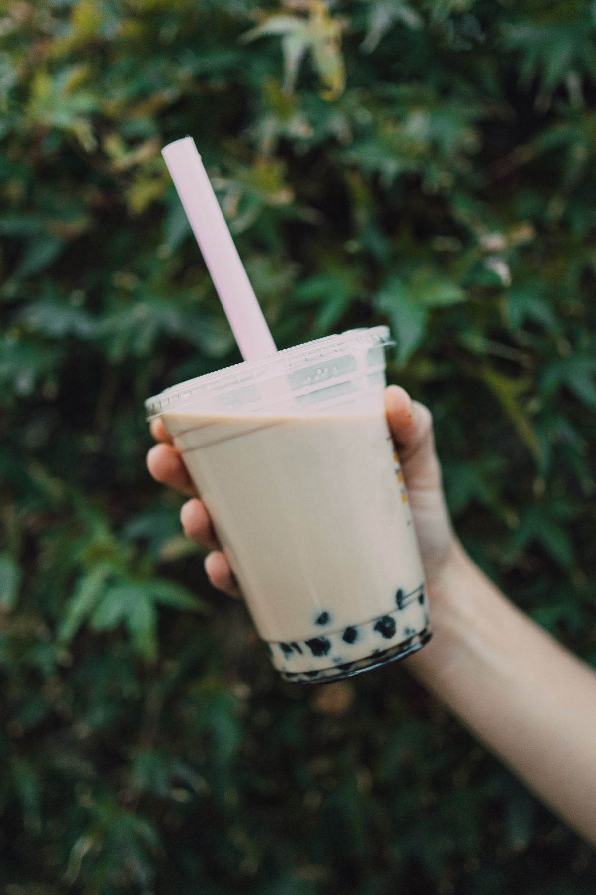 Bubble Tea in der Hand vor grünem Hintergrund